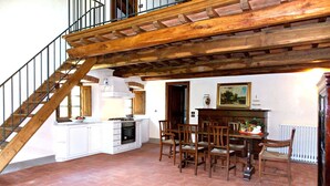 Una cocina con comedor, escalera de madera y un radiador.