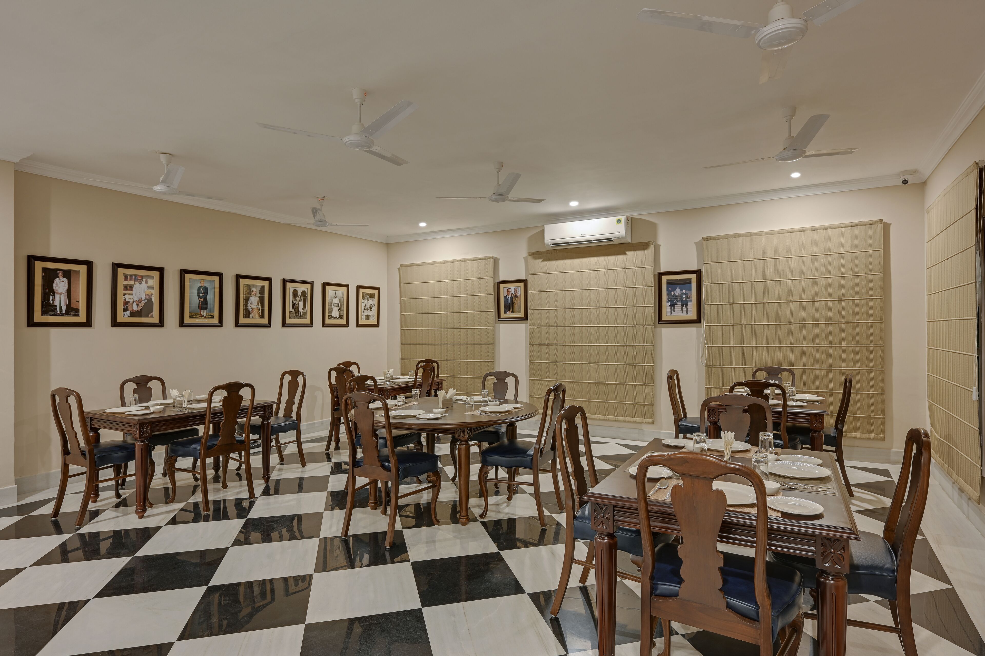 A dining area with multiple tables and chairs, ceiling fans, and framed pictures on the walls.