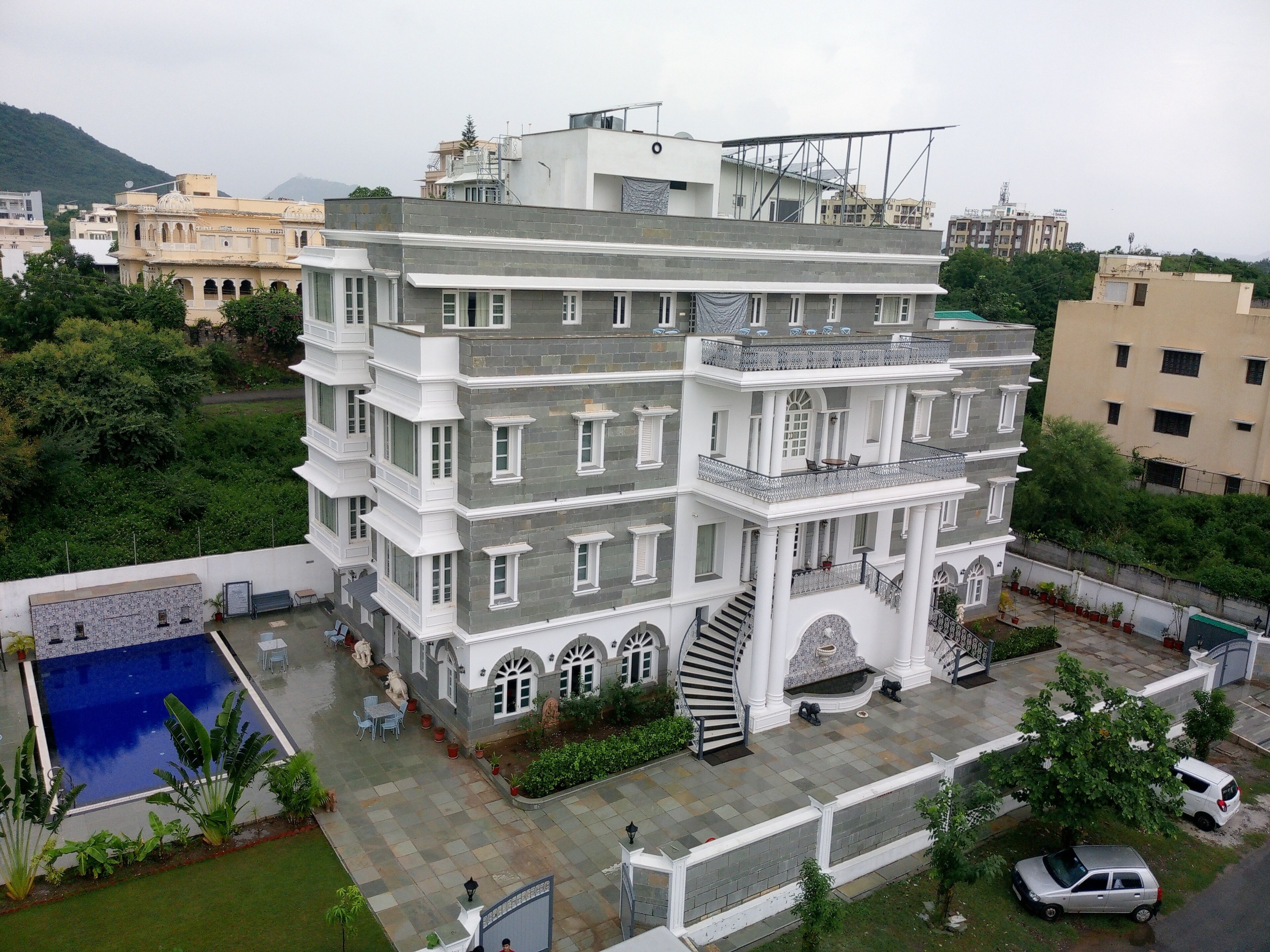 Un edificio de varios pisos con piscina, zona de estar exterior y una escalera que lleva a un balcón.