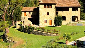 A stone house with a tiled roof, surrounded by a well-maintained lawn and trees. - Nice apartment for 2 guests with WIFI, pool, TV and pets allowed (Carbonile)