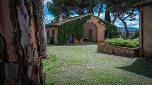 A rustic stone building with an arched entrance, surrounded by a gravel courtyard and lush greenery. - Stunning private villa for 11 people with A/C, WIFI, TV and patio (Follonica)