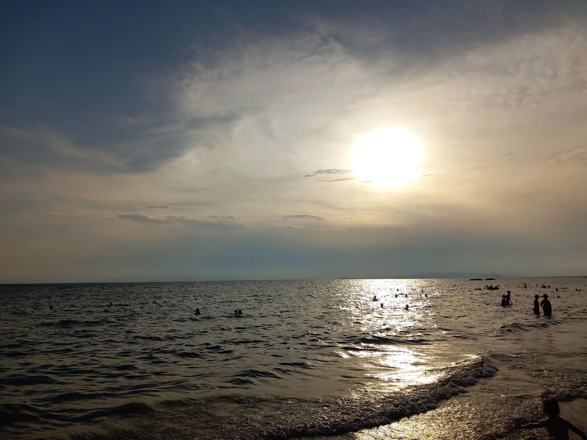 Una spiaggia con il sole che tramonta sull'acqua, creando un'atmosfera tranquilla.