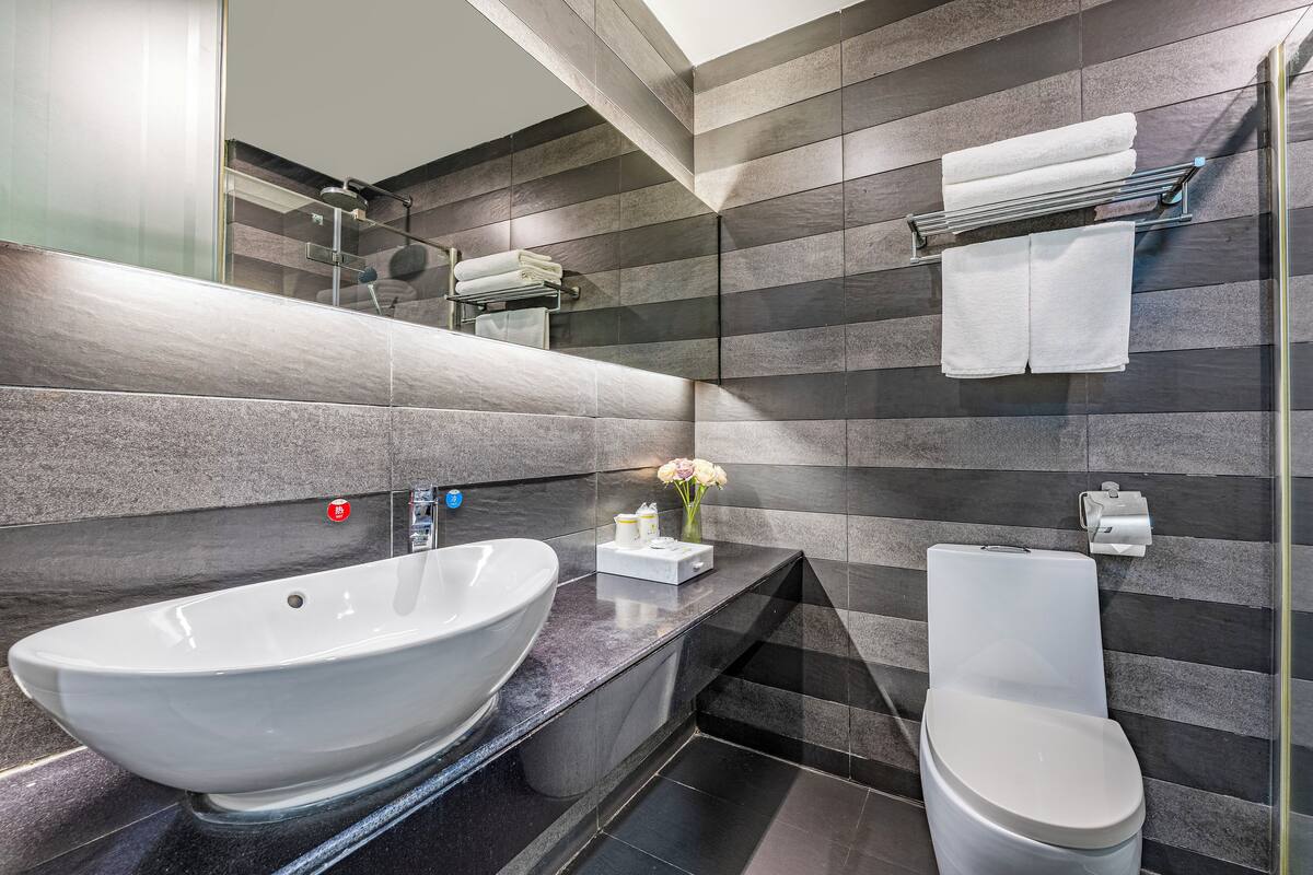 Un baño moderno con un lavamanos grande de color blanco, un inodoro y una zona de ducha.