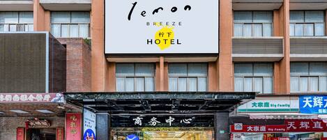 Un hotel con un letrero grande que dice "Breeze Hotel" y varios comercios en la planta baja.