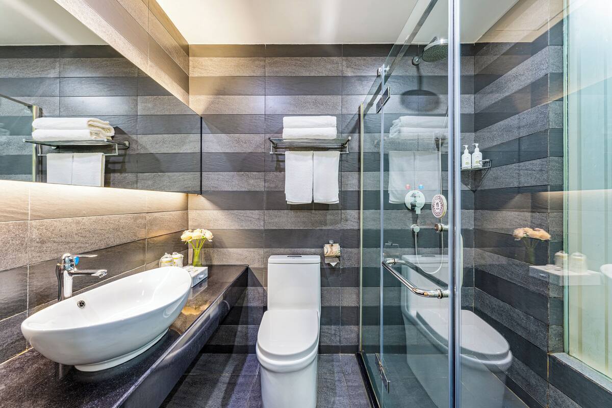 Un baño moderno con una bañera independiente, inodoro y ducha con mampara de vidrio.