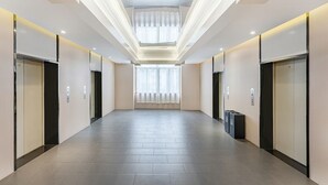 A modern hallway with elevators and a large window at the end.