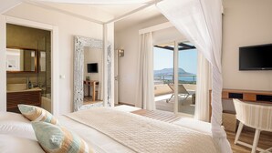 A bedroom with a large bed, a TV, and a balcony with a view of the sea.