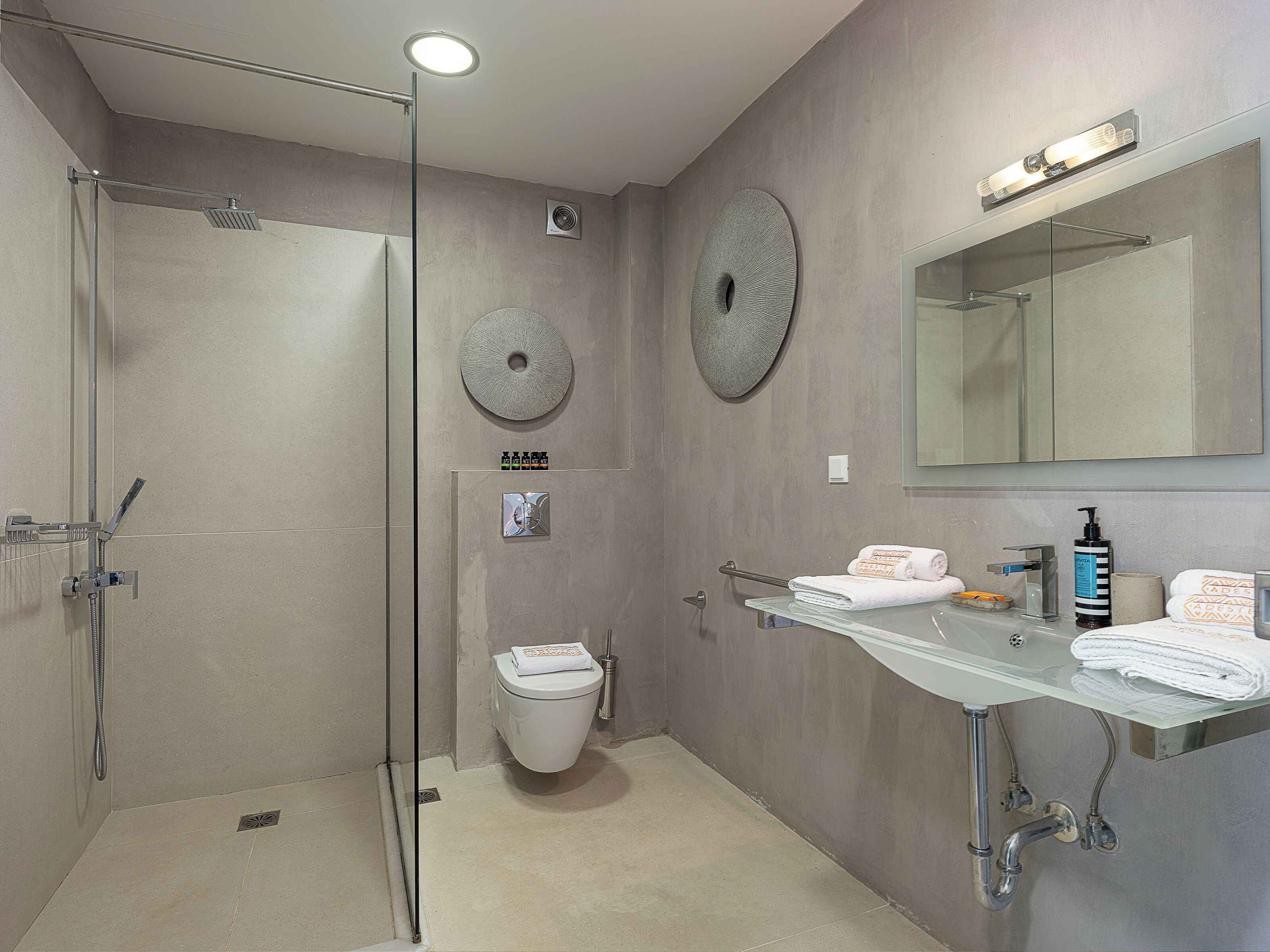 A modern bathroom with a glass shower enclosure, a toilet, a sink with a mirror, and a towel rack.