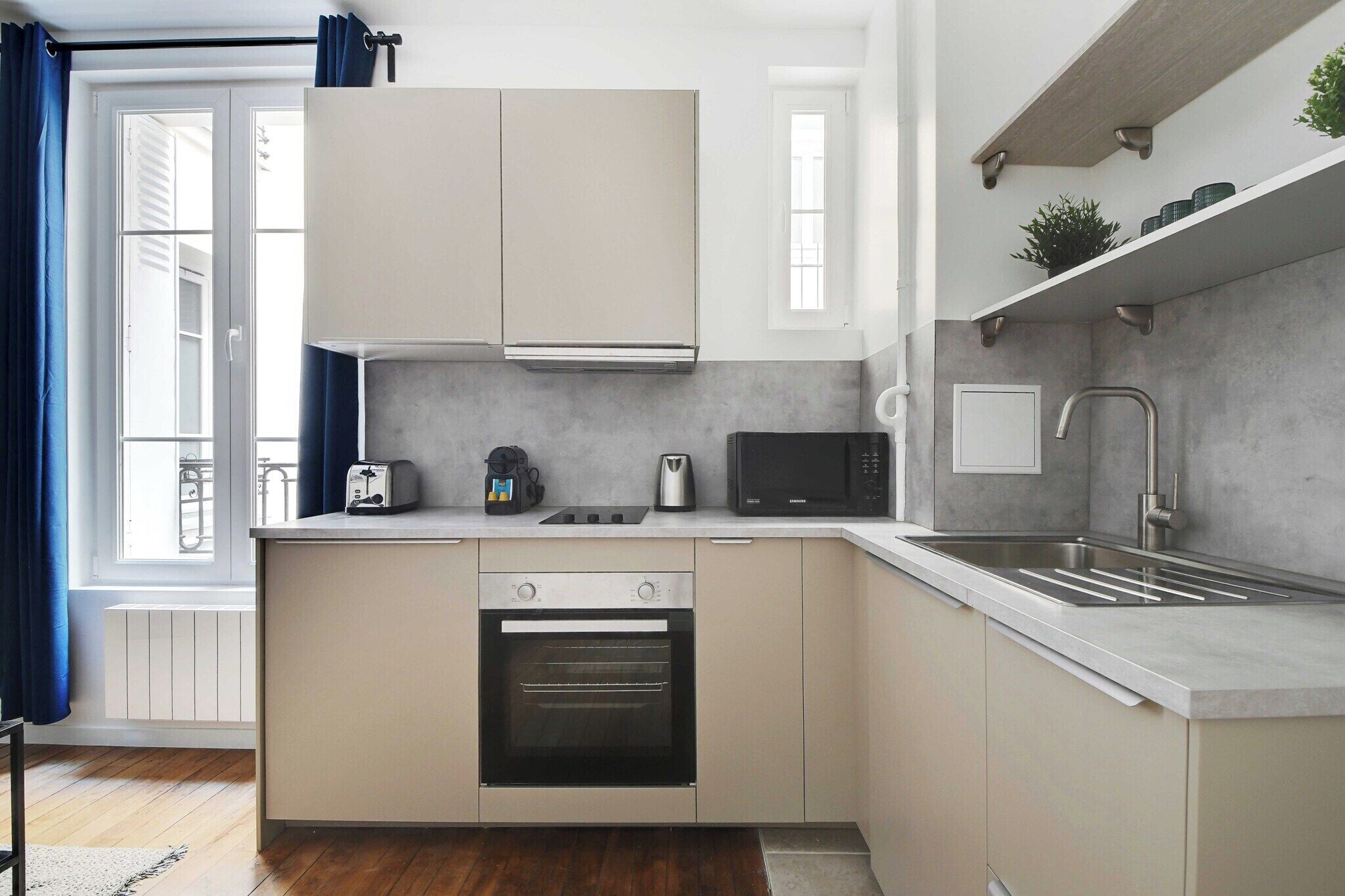 A modern kitchen with a built-in oven, a microwave, and a stainless steel sink.