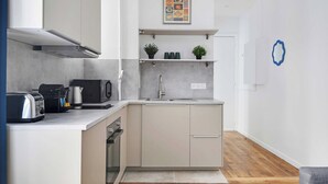 Une cuisine moderne équipée d’un grille-pain, d’une bouilloire et d’un four à micro-ondes. On y trouve un évier et une étagère avec des plantes.