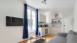 Un salon moderne avec un canapé gris, une table basse en verre et un téléviseur à écran plat fixé au mur.