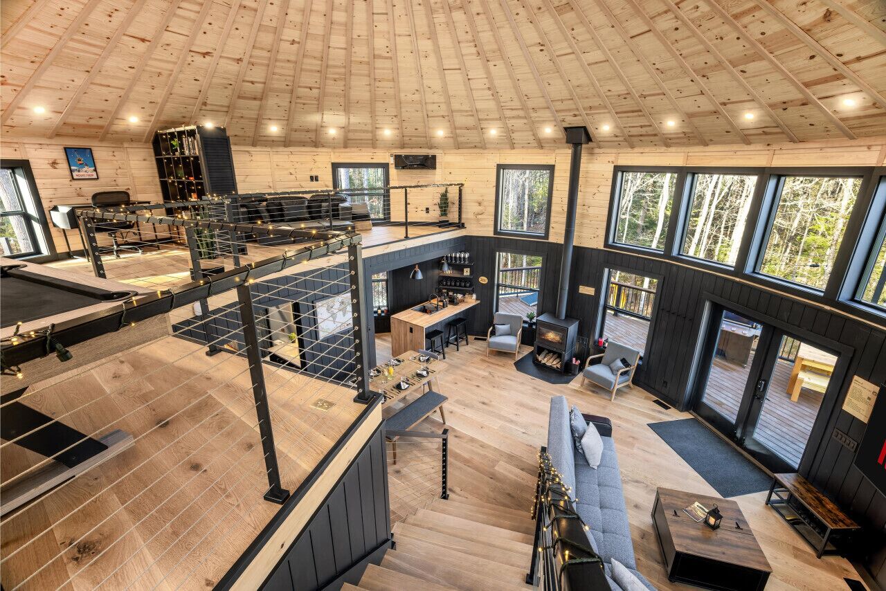 A spacious interior with a high ceiling, a kitchen area, a dining space, and a seating area with a fireplace.