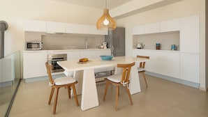 Une cuisine moderne avec des meubles blancs, un îlot central et un luminaire suspendu.