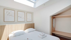 Una habitación de hotel con cama, tragaluz y obras de arte en la pared.