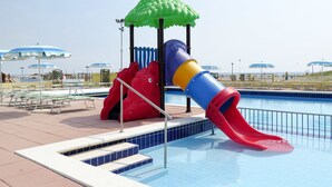 A poolside play area with a slide, a small playhouse, and umbrellas. - Rosolina Mare Club by Interhome (Rosolina Mare)