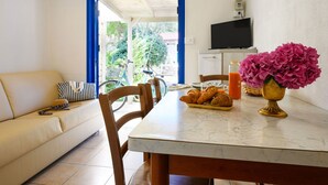 A dining area with a table set for breakfast, including croissants and juice, and a sofa with a striped pillow. - Rosolina Mare Club by Interhome (Rosolina Mare)