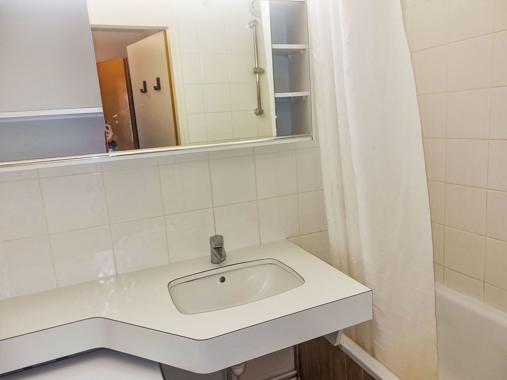 A bathroom with a white sink, a mirror, and a shower curtain.