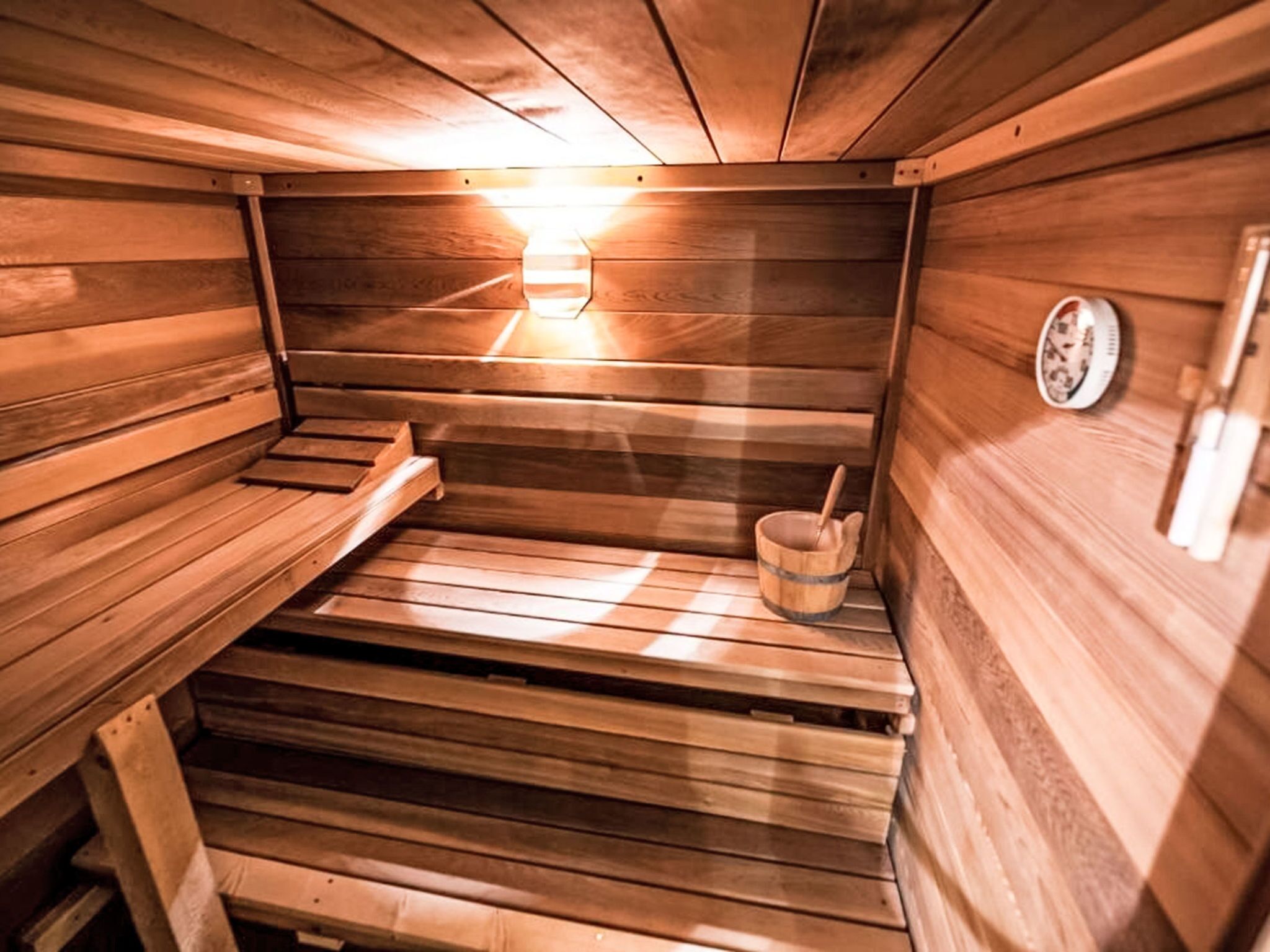 Un sauna en bois avec des bancs et un seau.