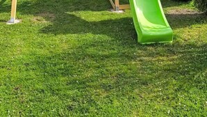 A wooden swing set with a green slide in a grassy yard. - Grimming by Interhome (Gröbming)