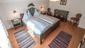 A bedroom with a wooden bed, a nightstand, a dresser, a chair, and a hanging light fixture. - Grimming by Interhome (Gröbming)