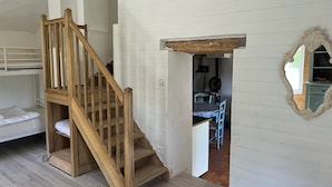A wooden staircase leading to a loft bed, a dining area with a table and chairs, and a mirror on the wall. - Domaine du Cruvelet (Trigance)