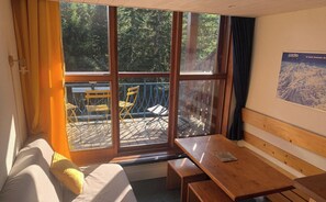 A room with a sliding glass door leading to an outdoor deck with chairs and a table.