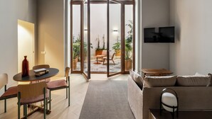 Een moderne woonkamer met een bank, een salontafel en een eethoek met stoelen en een tafel.