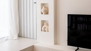 Ein modernes Interieur mit einer Treppe zu einer Tür, einem an einer weißen Wand montierten Flachbildfernseher und einer Deckenleuchte.