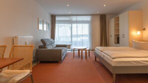 Et hotelværelse med seng, sofa, spisebord og et lille bord.