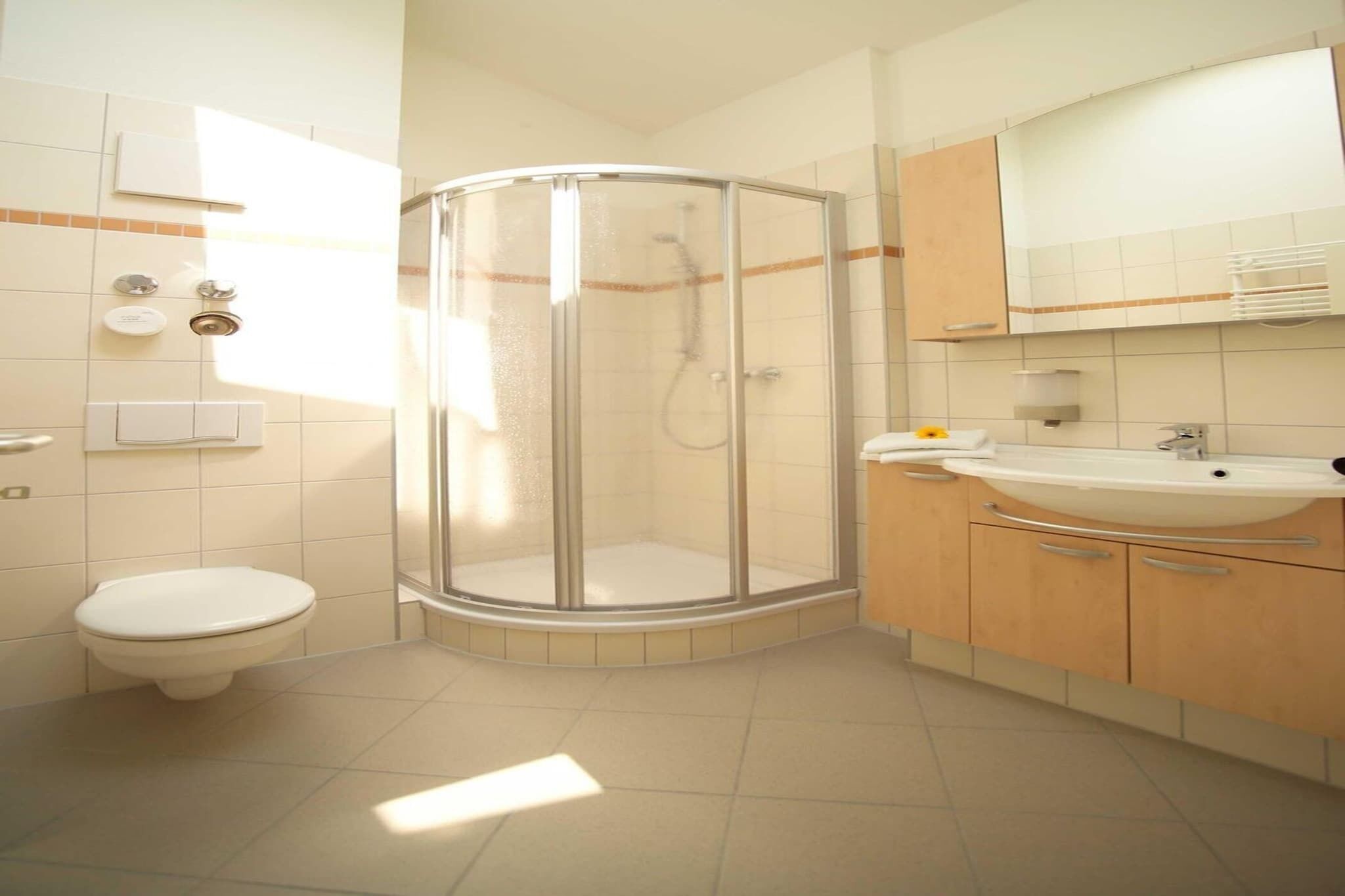 Un bagno con cabina doccia in vetro, un water, un lavandino e uno specchio.