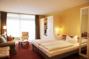 A hotel room with two beds, a sofa, a small table, and a TV. - Apartment für den perfekten Urlaub (Granzow)