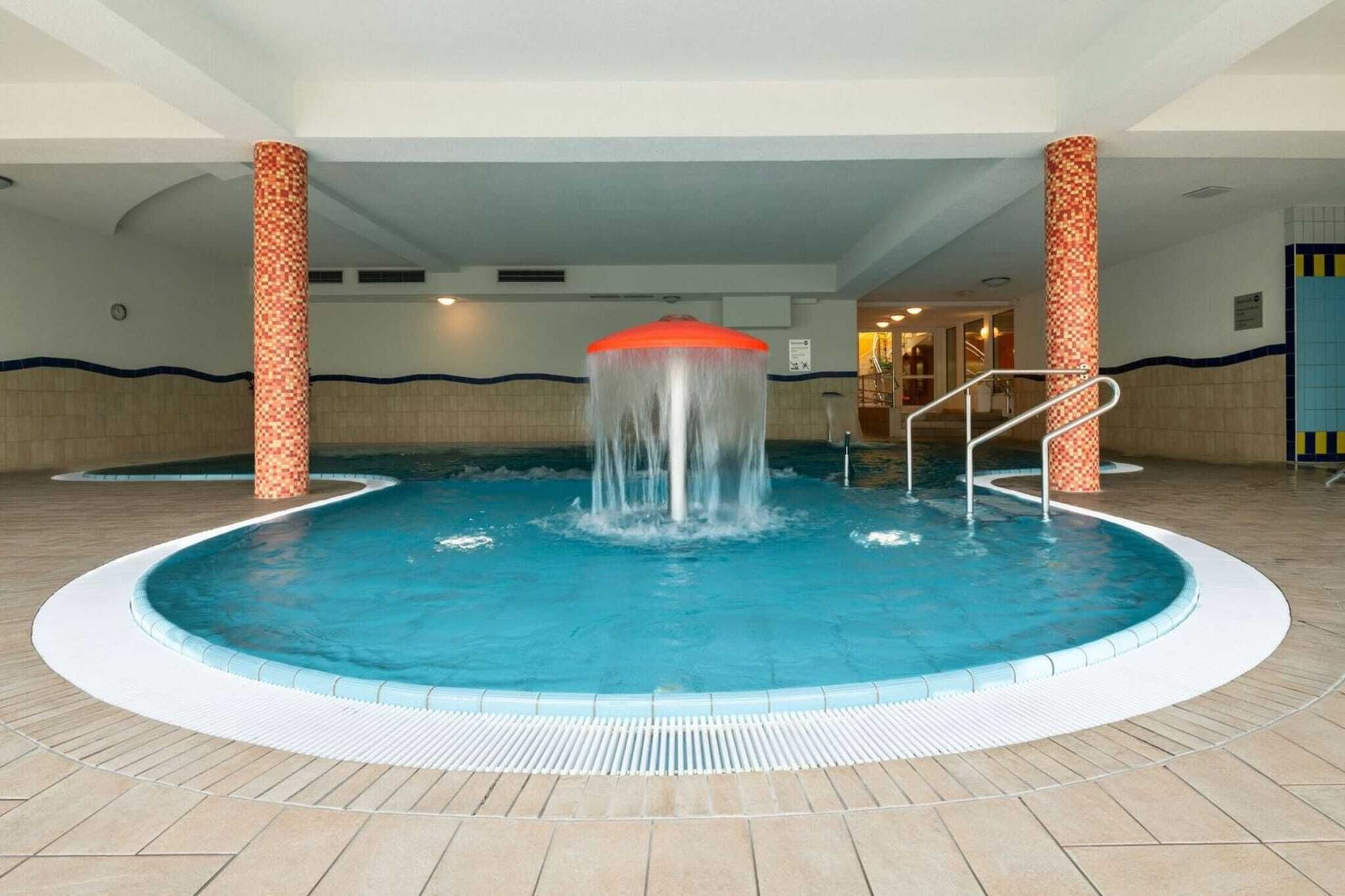 A swimming pool with a central water feature and steps leading into the pool.