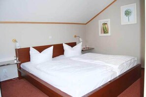 Une chambre à coucher avec un lit double, des tables de chevet, une commode et des lampes fixées au mur.