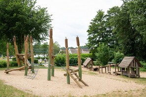 Un parque infantil con estructuras para escalar y una zona de juegos con arena.