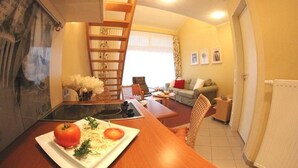En kompakt opholdsstue med spisebord, sofa, stol, trappe og en radiator.