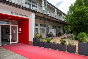 Un edificio con entrada roja y un balcón con sombrillas.