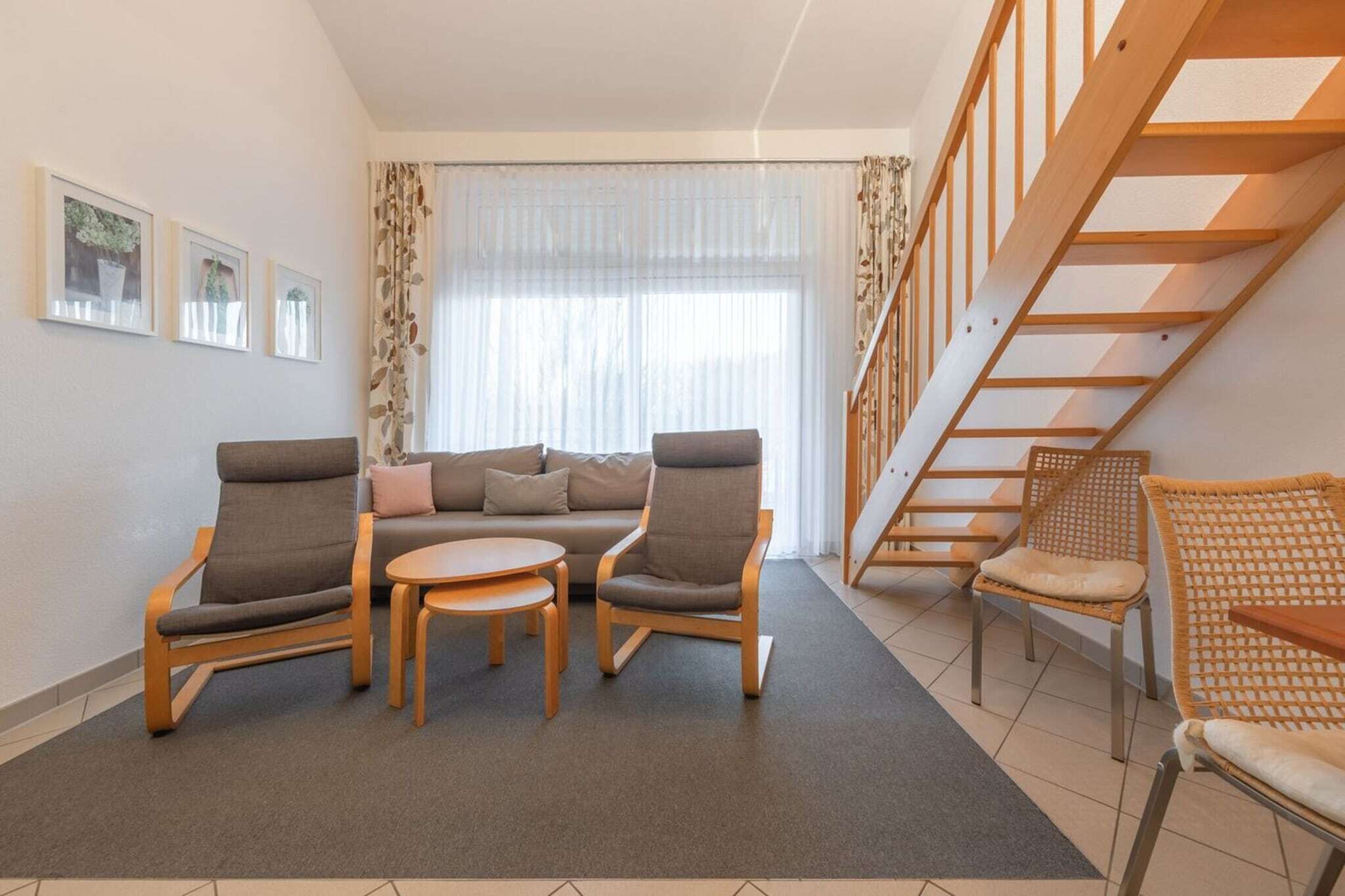 Ein modernes Wohnzimmer mit einer Couch, zwei Sesseln, einem Couchtisch und einer Treppe.