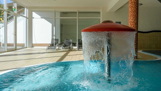 A pool with a water feature, indoor seating area, and large windows. - Elegant eingerichtete Ferienwohnung (Granzow)