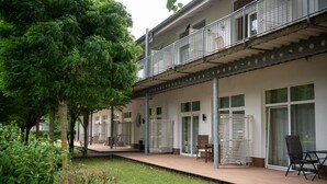 A modern building with a covered outdoor area, including a patio with chairs and a table. - Elegant eingerichtete Ferienwohnung (Granzow)