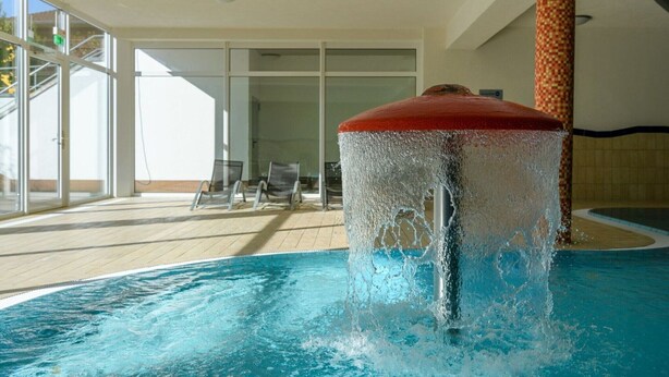 A swimming pool with a water fountain, indoor seating area, and large windows. - Appartement mit skandinavischem Flair (Granzow)