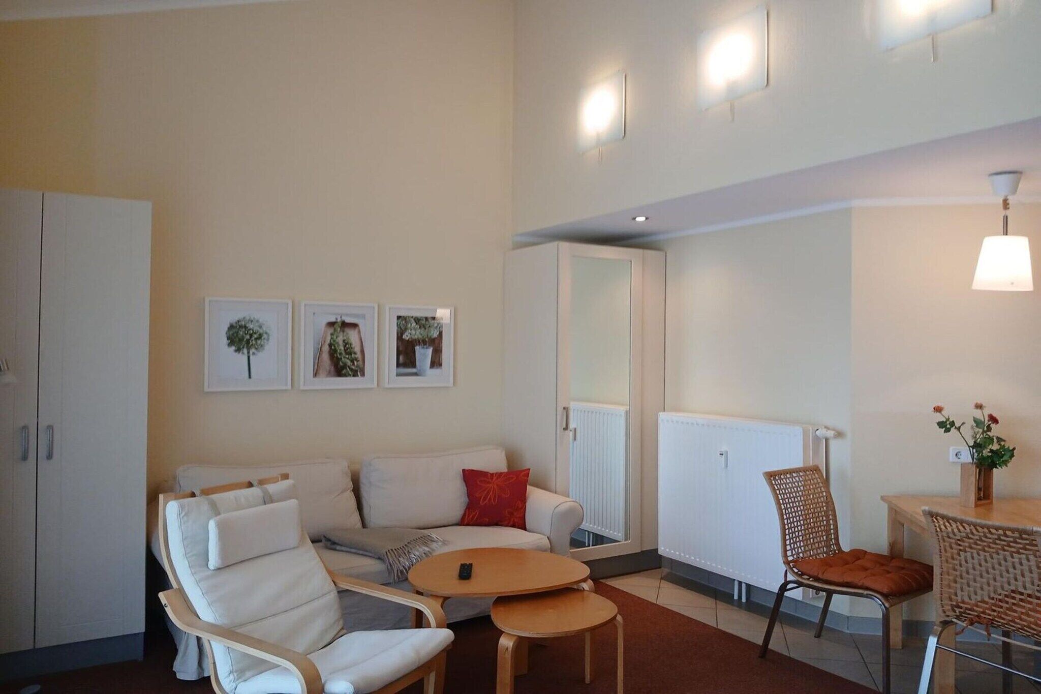 A modern living room with a sofa, armchairs, a small table, and a dining area with a chair and table.