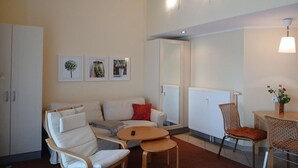 A modern living room with a sofa, armchairs, a small table, and a dining area with a chair and table.