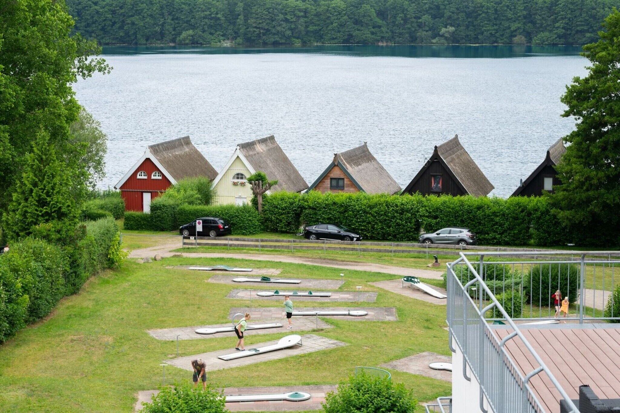 Blick auf einen See mit traditionellen Häusern, einem Schwimmbereich und einer eingezäunten Terrasse.