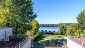 A view of a lake with a wooden deck and a grassy area in the foreground. - elegant eingerichtete Ferienwohnung (Granzow)