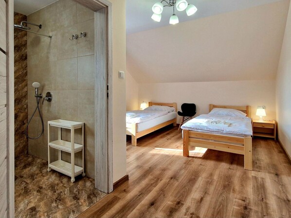 Un dormitorio con dos camas, ducha y suelo de madera.