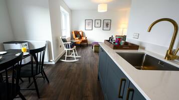 A modern kitchen with a white countertop, a stainless steel sink, and a wooden dining table with chairs.