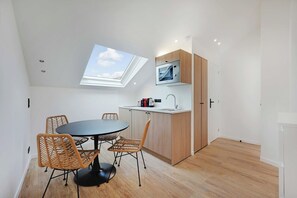 Una cocina moderna con microondas integrado, un comedor con sillas de mimbre y un tragaluz.