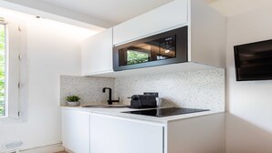 A modern kitchen with white cabinetry, a built-in microwave, and a small countertop.
