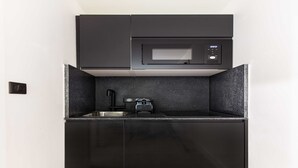 A compact kitchen with a microwave, sink, and black cabinets. - Cosy Studio - Parc des expositions / Tour Eiffel 11 (Paris)