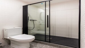 A modern bathroom with a toilet, a glass-enclosed shower, and a patterned wall. - Cosy Studio - Parc des expositions / Tour Eiffel 11 (Paris)